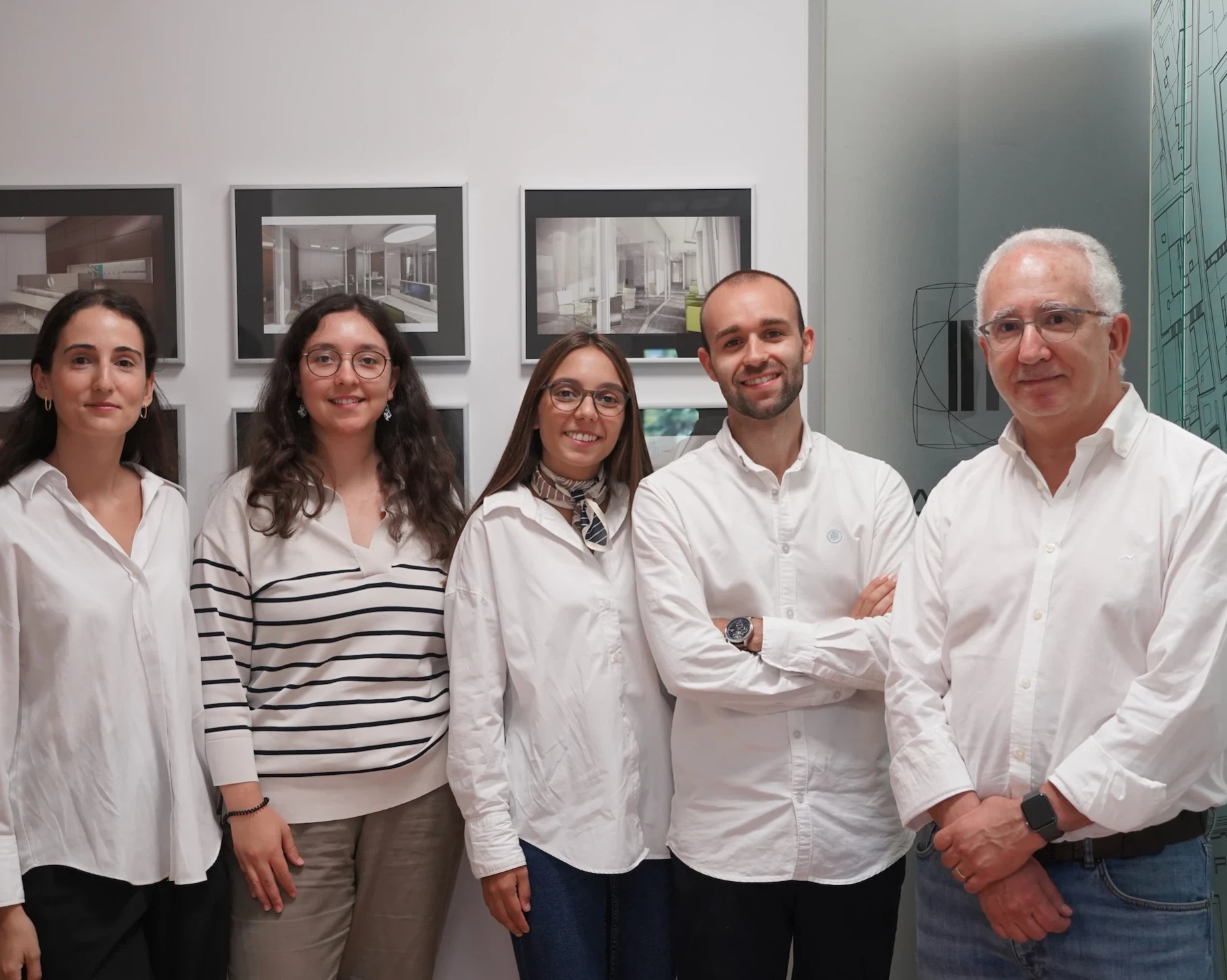 Os cinco elementos da equipa do Atelier Geometria no escritório, junto à parede com projetos emoldurados