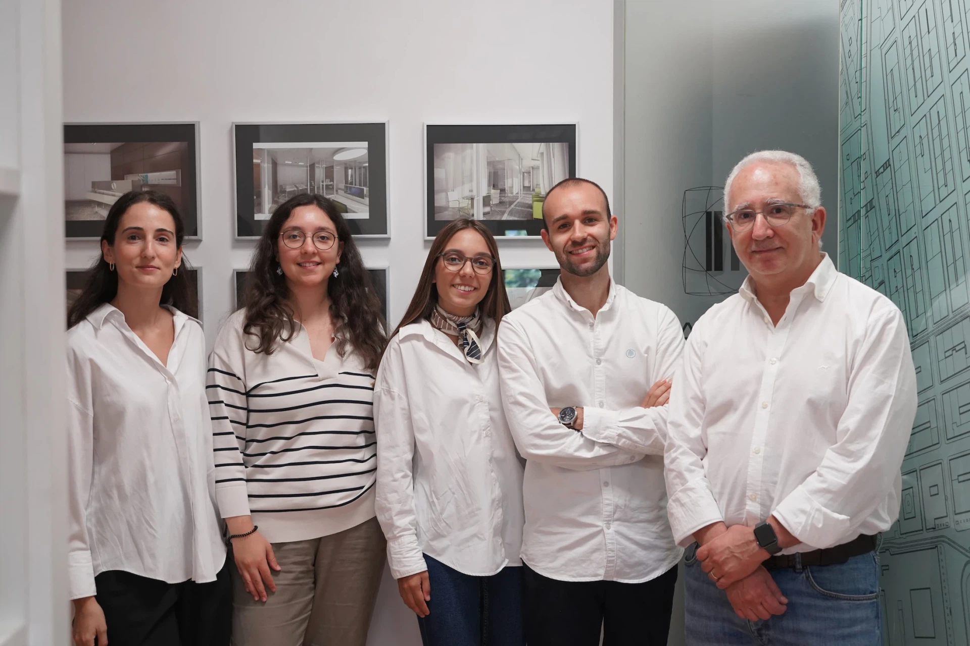 Os cinco elementos da equipa do Atelier Geometria no escritório, junto à parede com projetos emoldurados